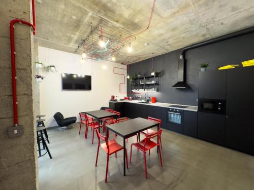 a kitchen with tables and red chairs in a room at ROCH800 - industriální aparthotel Klatovy in Klatovy