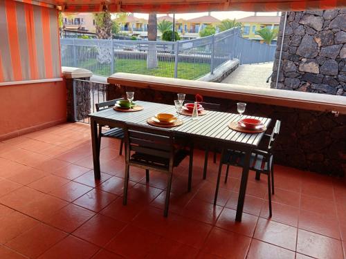 ein Holztisch und Stühle auf einem Balkon mit einem Tisch und Getränken in der Unterkunft Atlantico breeze in Costa Del Silencio