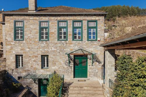 a brick building with a green door and windows at panacea zagori in Tsepelovo