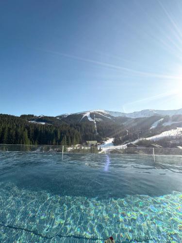 a pool of water with mountains in the background at Swissôtel Damian Jasna in Demanovska Dolina