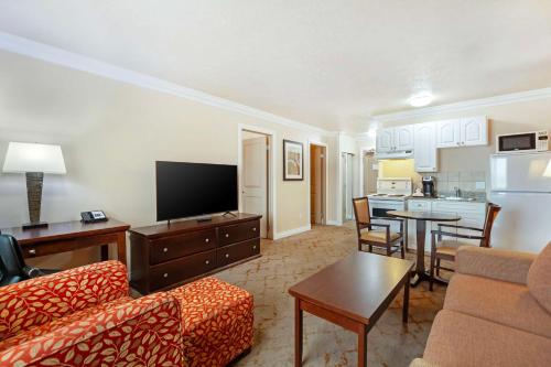 a living room with a couch and a tv and a kitchen at Best Western PLUS Mirage Hotel and Resort in High Level