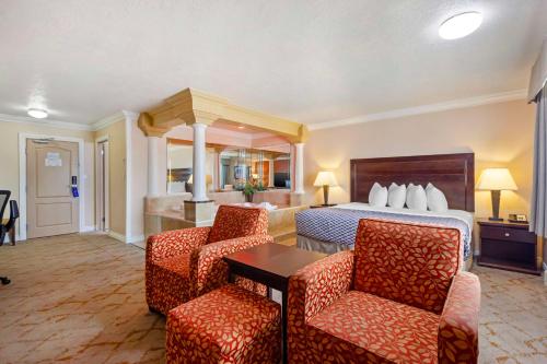 a hotel room with a bed and two chairs at Best Western PLUS Mirage Hotel and Resort in High Level