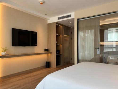 a bedroom with a bed and a tv on a wall at Laya Suites and Residences in Bang Tao Beach