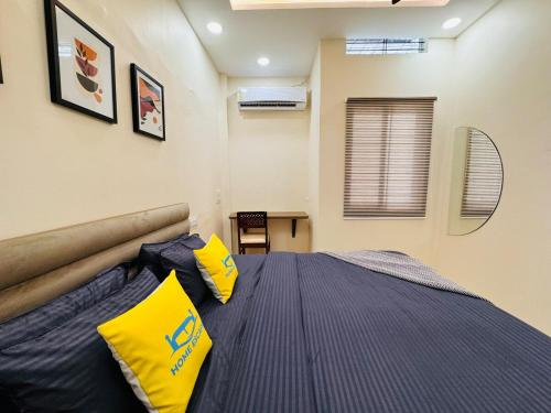 a bedroom with a bed with yellow pillows on it at Home Escape 2BHK Retreat Pvt Home in Ujjain