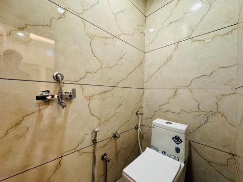 a bathroom with a toilet and a marble wall at Home Escape 2BHK Retreat Pvt Home in Ujjain