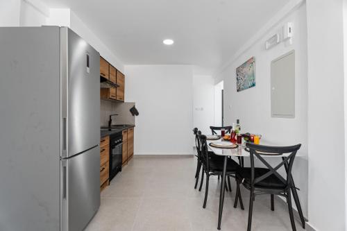 a kitchen with a table with chairs and a refrigerator at PANATHEON - Luxury 1 & 2 bdr bungalows 300 meters from sandy beach! in Ayia Napa