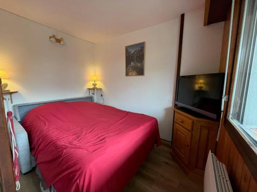 - une chambre avec un lit rouge et une télévision à écran plat dans l'établissement Cosy Criou - Appartement avec vue sur la montagne, à Samoëns