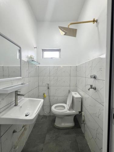 a white bathroom with a toilet and a sink at Villa Ekram Yusof - Klang in Klang