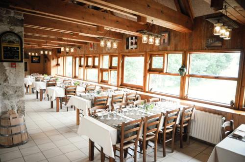 une salle à manger avec des tables et des chaises blanches et des fenêtres dans l'établissement Le Jas du Mas, à Saint-Anthème