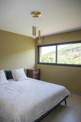 une chambre avec un grand lit avec une grande fenêtre dans l'établissement L'expérience Maison Augusta, à Salasc