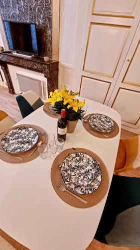 une table blanche avec trois assiettes et des fleurs dessus dans l'établissement Studio coeur Centre ville Troyes, à Troyes