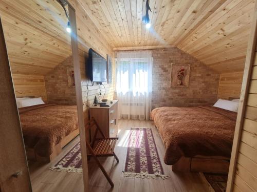 a bedroom with two beds in a wooden cabin at Pensiunea Poiana Cerbului in Tarcău-Gheuca