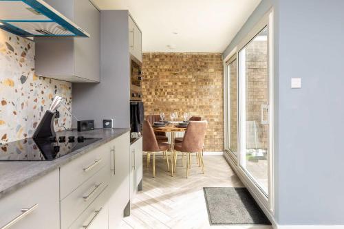 a kitchen with a table and a dining room at Modern & Stylish 3 Bedroom Home in Peterborough in Peterborough