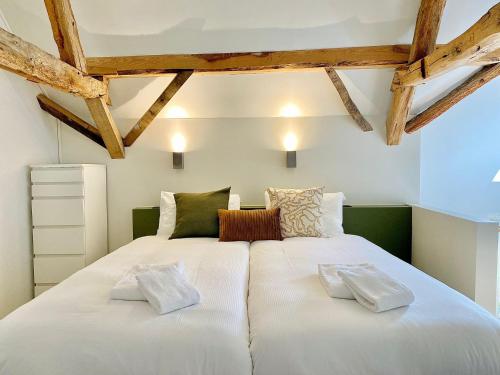 a large white bed in a room with wooden ceilings at Landgoed De Hoogmolen in Oudsbergen 