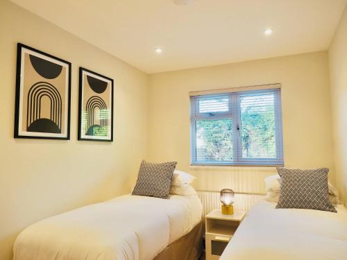 two beds in a room with a window at Spacious 3 bedroom Home w Parking in Farnborough in Farnborough