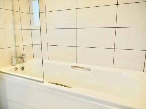 a white bath tub with a glass shower backdoor at Spacious 3 bedroom Home w Parking in Farnborough in Farnborough