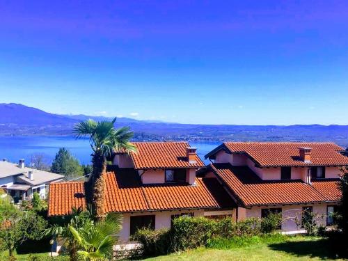 a house with orange tile roofs and a palm tree at Villa Vista Lago in Massino Visconti