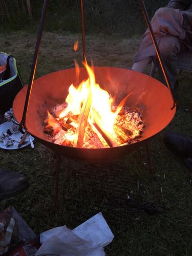 a fire in a red pot on a grill at Celtic Longhouse Tent at Coverack Camping in Coverack