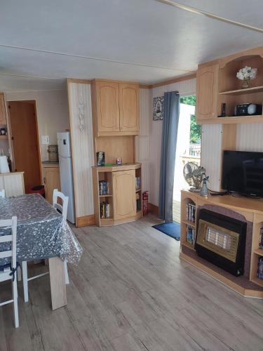 un salon avec une table et une cuisine dans l'établissement Mobil Home 3 chambres au Camping Paradis du Quinquis, à Clohars-Carnoët