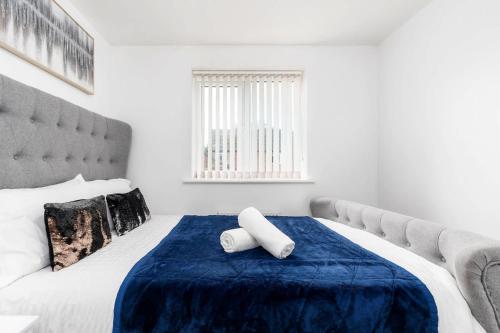 a bedroom with a large bed with a blue blanket at Charming 3 Bedroom Home with Garden near Doncaster in Doncaster