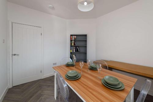 a dining room with a wooden table with plates and wine glasses at 3 Bedroom Spacious and Homely Welsh Retreat in Coelbren