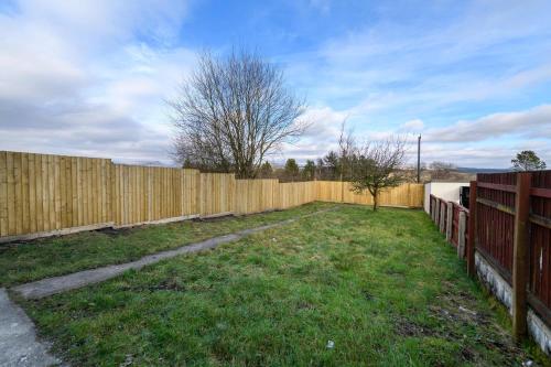 a wooden fence in a yard next to a field at 3 Bedroom Spacious and Homely Welsh Retreat in Coelbren