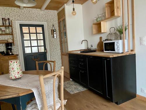 une cuisine avec une table et un four micro-ondes sur un comptoir dans l'établissement Chambre d'hôte Le CLOS LILAS, à Paimpol