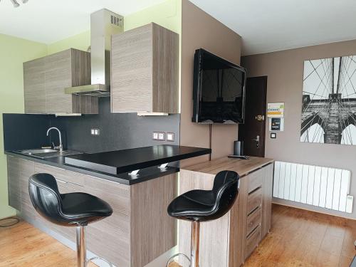 a kitchen with a counter and two black stools at Le Moderne in Saint-Julien-en-Genevois