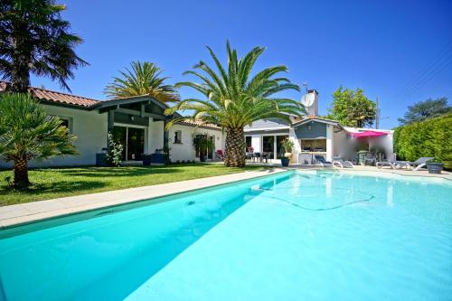 une piscine devant une maison avec des palmiers dans l'établissement Très belle villa avec piscine, à Biarritz