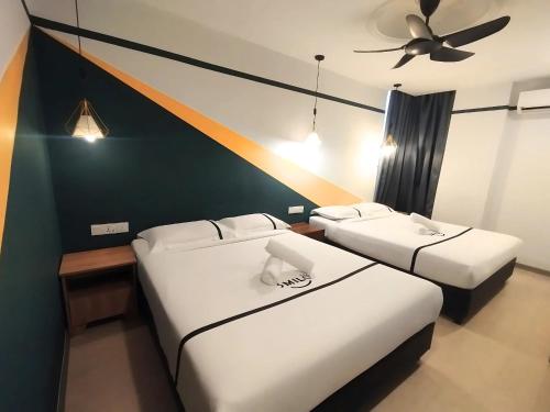 two beds in a room with a ceiling fan at Smile Hotel C180 Cheras Selatan in Cheras