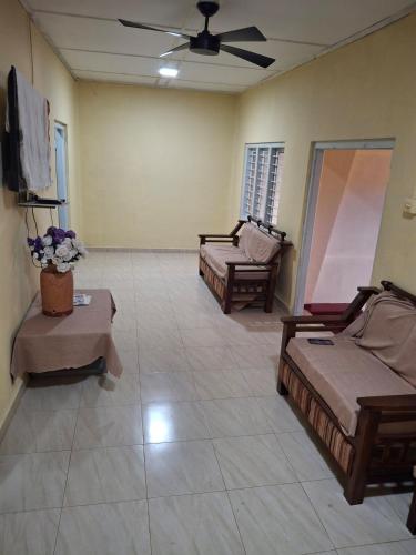 a living room with two beds and a ceiling fan at SKK Guest House in Urumpirai