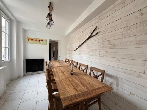 Cette chambre comprend une grande table et des chaises en bois. dans l'établissement Embruns maison 5 ch 3 sdb belle terrasse aménagée barbecue 250 m de la mer en plein centre d' Arromanches au coeur des plages du débarquement, proximité de Bayeux, à Arromanches-les-Bains