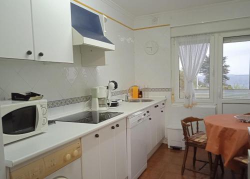 a white kitchen with a sink and a microwave at Apartamento Barro Playa in Barro de Llanes
