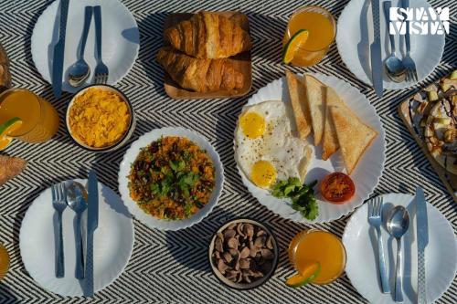 a table with plates of breakfast food on it at StayVista at Riverside Symphony - Bonfire, BBQ, WiFi in Manāli