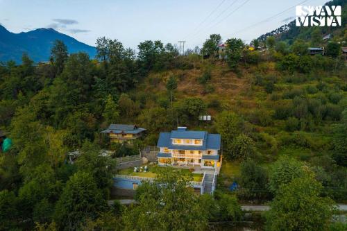 an aerial view of a house on a hill at StayVista at Riverside Symphony - Bonfire, BBQ, WiFi in Manāli