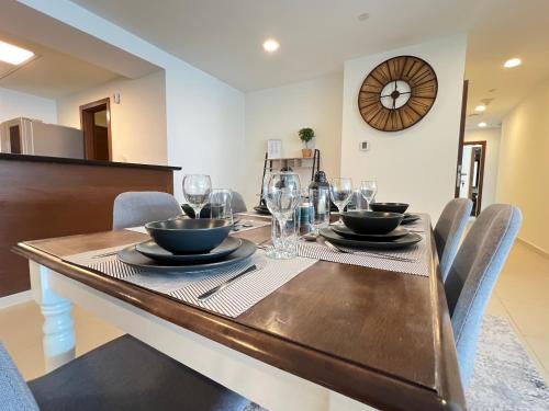 a dining room with a table with chairs and a clock at HighFloor 3BR plus Maids GateTower in Abu Dhabi