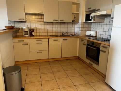 a kitchen with white cabinets and a tile wall at PALMERAIE 325 in Sari Solenzara