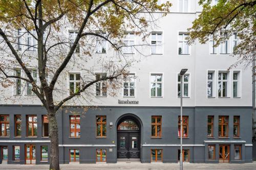 a white building with a black door and a tree at Limehome Berlin Stresemannstr in Berlin