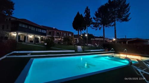 a swimming pool lit up at night at Hotel Rural VN Casal in Pontevedra
