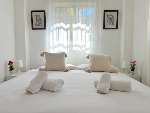 a white bed with white pillows on top of it at GARDEN HOUSE Malaga City in Málaga