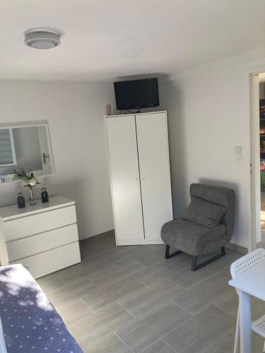 - une chambre avec une chaise, une armoire et une télévision dans l'établissement Chambre comme un petit logement, à Cholet