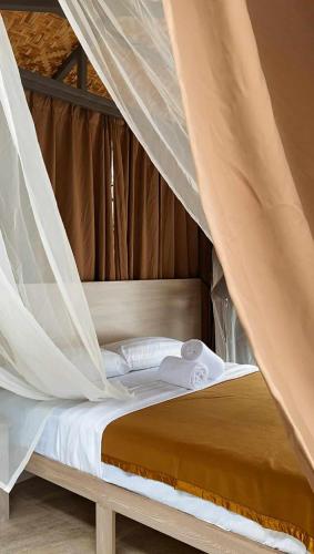 a bed with a canopy with white sheets and pillows at The South Hideaway Oslob 