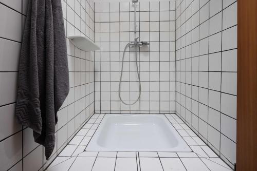 a bathroom with a shower with a white tiled floor at Kapelle Elbtalaue - Sakristei in Hitzacker
