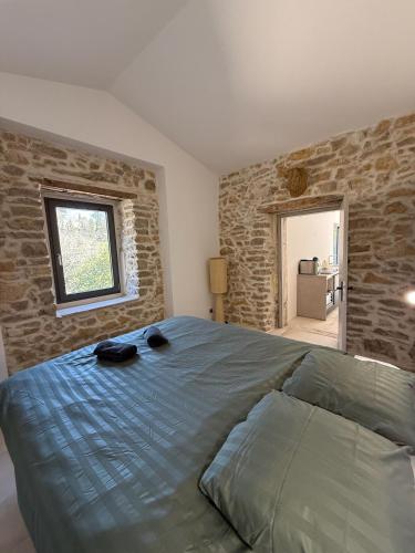une chambre avec un lit et un mur en pierre dans l'établissement Le Mazet, Dépendance au cœur de la garrigue, à Nîmes