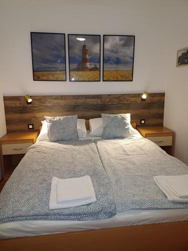 a bedroom with a large bed with three pictures on the wall at Apartman BoloB in Baška