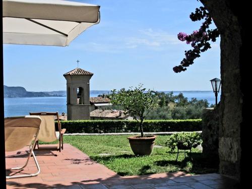 a patio with a view of the water and a tower at Dolce Vita- x8 Luxury Garda Lake in Gardone Riviera