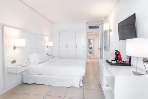 a white bedroom with a bed and a tv at Landmar Costa los Gigantes Family Resort in Puerto de Santiago
