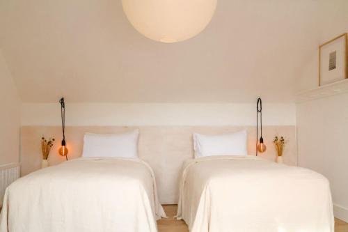 two beds in a room with white sheets at Kelp Lodge in Doolin