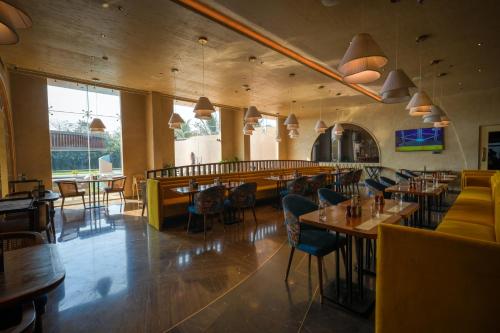a restaurant with tables and chairs and a bar at Palm Springs Resort in Nashik