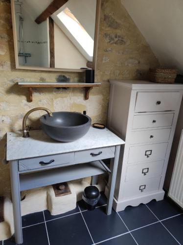 La salle de bains est pourvue d'un lavabo et d'une coiffeuse avec un miroir. dans l'établissement La Cour Souveraine - Chambre d'hôtes La Péninsule, à Mosles